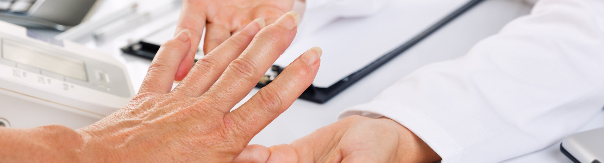 Ärztin untersucht Hand und Finger von Patientin