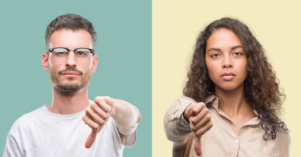 Un jeune homme et une jeune femme montrent leur pouce vers le bas